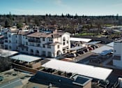 Thumbnail 21 of 61 - A large white building with a red roof is surrounded by other buildings.