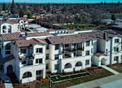 Thumbnail 15 of 61 - A large white building with a red roof is surrounded by smaller buildings.