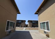 Thumbnail 20 of 25 - A view of a courtyard between two buildings with a clear blue sky above.
