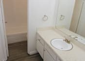 Thumbnail 12 of 17 - A bathroom with a sink, mirror, and wooden floor.