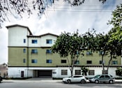 Thumbnail 108 of 127 - A white and beige building with a parking lot in front.