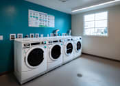 Thumbnail 111 of 127 - Three front load washing machines are lined up in a laundry room.
