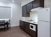 Thumbnail 118 of 127 - A kitchen with a white refrigerator, brown cabinets, and a white countertop.