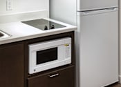 Thumbnail 123 of 127 - A white refrigerator stands next to a microwave in a kitchen.