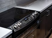 Thumbnail 121 of 127 - A modern kitchen with a black stove top oven and wooden cabinets.