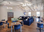 Thumbnail 106 of 127 - A room with a blue couch, chairs, and tables.