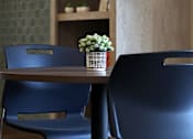 Thumbnail 98 of 127 - Two blue chairs are placed in front of a wooden table with a vase of flowers on it.