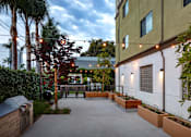 Thumbnail 90 of 127 - A patio area with a table and chairs surrounded by trees and plants.