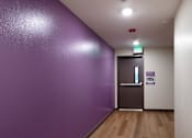 Thumbnail 85 of 127 - A hallway with a purple wall and wooden floor.