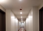 Thumbnail 83 of 127 - A long hallway with wooden floors and white walls.