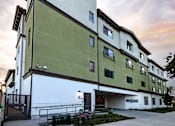 Thumbnail 72 of 127 - A building with a white and green facade is shown with a cloudy sky in the background.