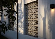 Thumbnail 75 of 127 - A wall with a patterned window and a light on.