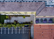 Thumbnail 64 of 127 - A parking lot is surrounded by a building with a red roof.