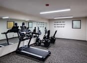 Thumbnail 54 of 127 - A gym room with treadmills and elliptical machines.