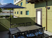 Thumbnail 39 of 127 - A patio with a table and chairs and a blue umbrella.