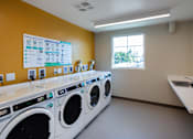 Thumbnail 46 of 127 - A laundromat with a row of washers and dryers.