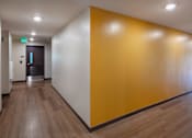 Thumbnail 29 of 127 - A hallway with a wooden floor and a yellow wall.