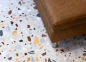 Thumbnail 27 of 127 - A brown leather chair is placed on a floor with multicolored tiles.