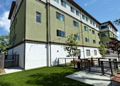 Thumbnail 21 of 127 - A modern building with a white and green exterior and a small courtyard in front.