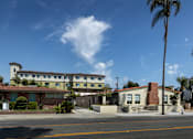 Thumbnail 4 of 127 - A building with a red roof and a white fence is in the foreground.