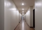 Thumbnail 11 of 127 - A long hallway with wooden floors and white walls.