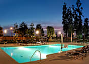 Thumbnail 97 of 117 - A pool surrounded by trees and chairs at night.