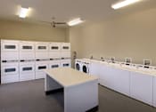 Thumbnail 98 of 117 - A room with a table and a wall of washing machines.