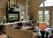 Thumbnail 81 of 117 - A living room with a couch, a coffee table, and a fireplace.