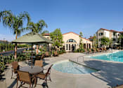 Thumbnail 77 of 117 - A pool surrounded by chairs and umbrellas with a building in the background.
