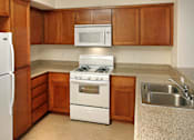 Thumbnail 114 of 117 - A kitchen with a white refrigerator, white stove, and brown cabinets.