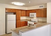 Thumbnail 113 of 117 - A kitchen with a white refrigerator, brown cabinets, and a white stove top oven.
