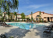 Thumbnail 18 of 117 - A pool surrounded by chairs and a building in the background.