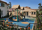 Thumbnail 26 of 117 - A playground with a slide and swings in front of a house.