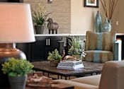 Thumbnail 24 of 117 - A living room with a lamp, a couch, and a table with a plant on it.