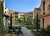 Thumbnail 3 of 117 - A pathway leads through a landscaped courtyard between two rows of apartment buildings.