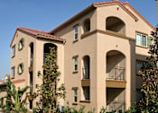 Thumbnail 5 of 117 - A beige building with a red tile roof and balconies.