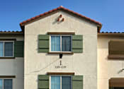 Thumbnail 16 of 117 - A two-story building with a tan facade and green shutters.