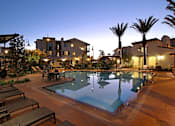 Thumbnail 3 of 45 - A pool surrounded by palm trees and lounge chairs.