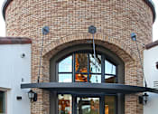 Thumbnail 7 of 45 - A building with a large arched doorway and a planter in front.