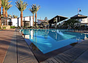 Thumbnail 9 of 45 - A pool surrounded by palm trees and a patio area.