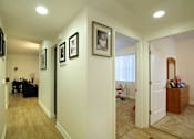 Thumbnail 10 of 45 - A hallway with a black couch and pictures on the wall.