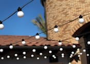 Thumbnail 14 of 45 - A string of white lights hangs in front of a building with a red tile roof.