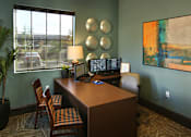 Thumbnail 34 of 45 - A room with a desk, chairs, and a painting on the wall.