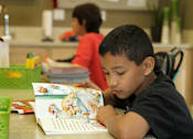 Thumbnail 11 of 126 - A young boy is reading a book in a classroom setting.