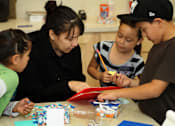 Thumbnail 9 of 126 - A woman and two children are working on a craft project together.
