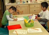 Thumbnail 37 of 126 - Two children are sitting at a table with school supplies and papers.