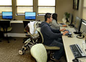 Thumbnail 36 of 126 - A man and woman are working on computers in an office with a baby in a stroller.