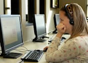 Thumbnail 42 of 126 - A woman is sitting in front of a computer with a headset on.