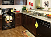 Thumbnail 48 of 126 - A kitchen with a black stove and wooden cabinets.