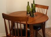 Thumbnail 33 of 126 - A wooden table with two chairs and three bottles on it.